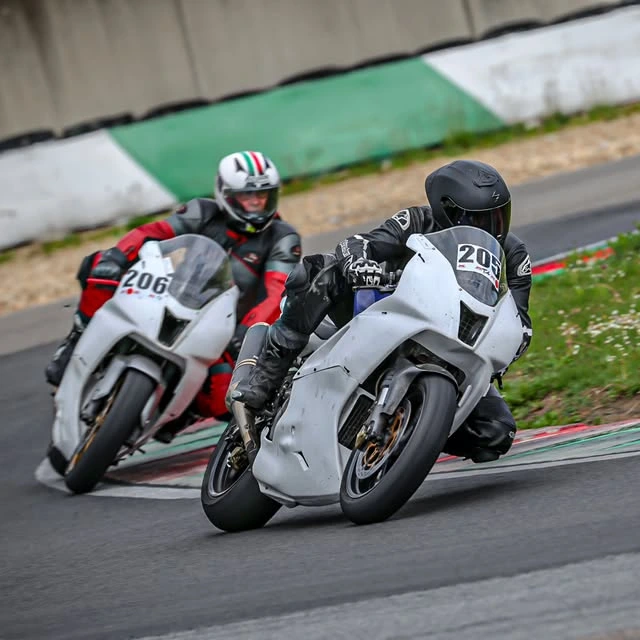 Vater und Sohn auf weißen Rennmotorrädern gemeinsam in einer Kurve